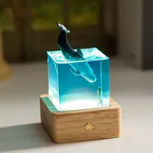 Glowing ocean whale resin night light featuring a diver and warm natural wooden base