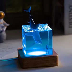 Detailed view of ocean whale resin night light with blue LED glow on wood base
