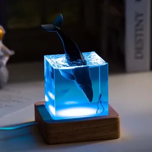 Close-up of a blue resin ocean whale night light on a wooden base for home decor