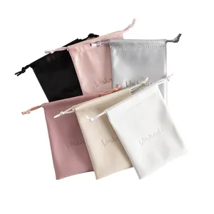 Detailed view of multiple colored PU leather drawstring pouches featuring embossed logo detail