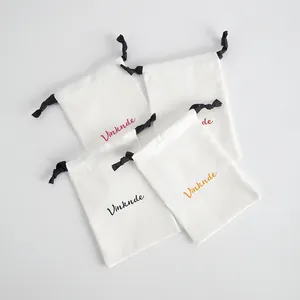 Cuatro bolsas de algodón blanco con cordón para joyas con ejemplos de logotipos impresos