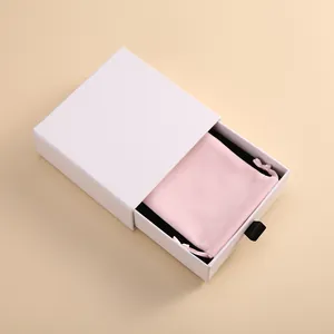 Detailansicht einer weißen Geschenkbox mit Schublade und rosa Samtbeutel mit Kordelzug