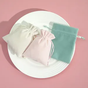 Κοντινό πλάνο από παστέλ βελούδινους σάκους για κοσμήματα σε λευκό κεραμικό πιάτο
