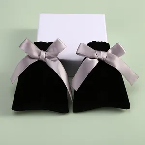 Gros plan détaillé de pochettes à bijoux en velours noir avec des nœuds en satin gris