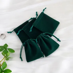 Vista detallada de bolsas de terciopelo verde oscuro para joyas con cordón y solapa de cierre