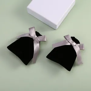 Détail de pochettes à bijoux en velours noir avec d'élégants nœuds en satin gris