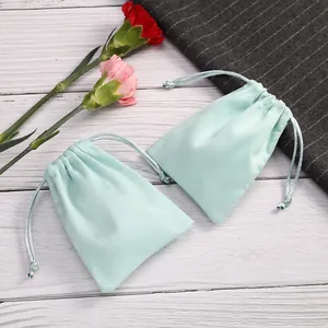 Detalle de bolsas de terciopelo verde menta con cordón para empaque de joyas