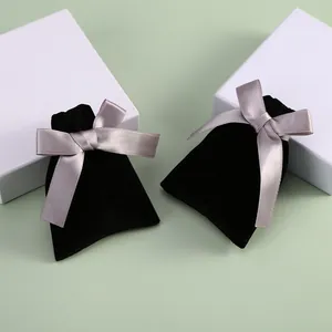 Vue détaillée de deux pochettes à bijoux en velours noir avec élégants nœuds en satin gris