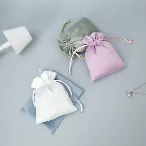 Colorful satin drawstring pouches for jewelry storage shown with decorative props.