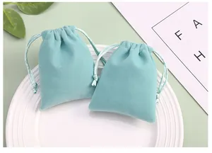 Gros plan de pochettes à cordon en velours pour bijoux, couleur bleu sarcelle, sur une assiette