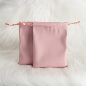 Close-up of two premium pink PU leather drawstring pouches displayed on white faux fur background.