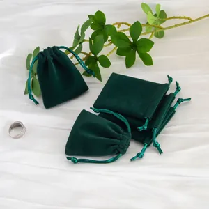 Vista detallada de bolsitas para joyas de terciopelo verde oscuro sobre tela blanca