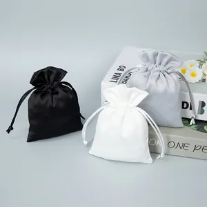 Close-up of premium satin drawstring gift pouches in black, white, and silver colors.