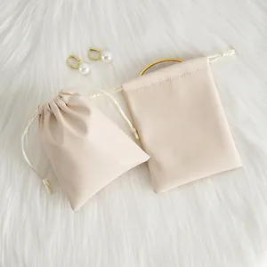 Close-up detail of beige PU leather drawstring jewelry pouches on soft white faux fur