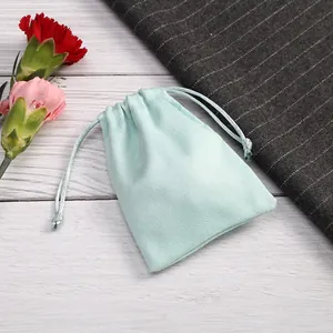 Primer plano de una bolsa de terciopelo verde menta con cordón para empaque de joyas.