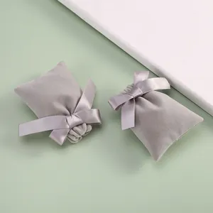 Close-up of grey velvet jewelry pouches with elegant satin ribbon bow details.