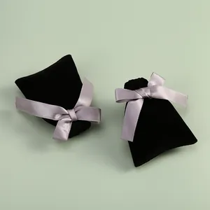 Vue détaillée de pochettes à bijoux en velours noir avec des nœuds en satin gris.