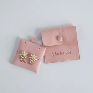 Close-up of a pink velvet jewelry pouch with a snap button and earring display card