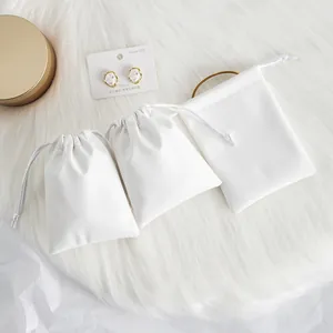 Detailed macro view of three white PU leather drawstring pouches for jewelry storage