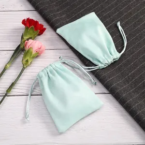 Primer plano de bolsas de terciopelo verde menta con cordón para joyas de alta gama