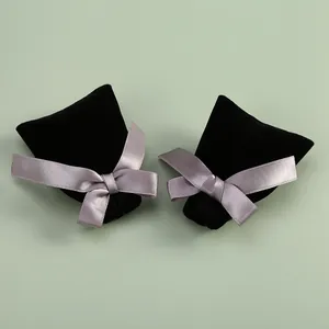 Détail de pochettes à bijoux en velours noir avec d'élégants nœuds en ruban gris sur vert