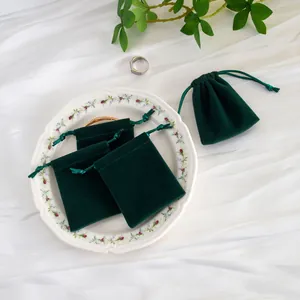 Vista detallada de bolsas de joyería de terciopelo microfibra verde oscuro con cordón ajustable.