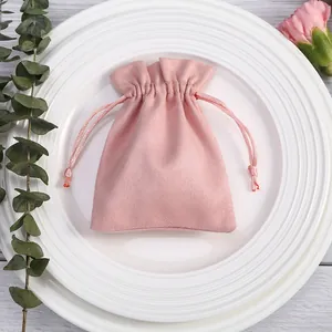 Λεπτομερής προβολή ροζ σουέτ πουγκί με κορδόνι για κοσμήματα πάνω σε λευκό πιάτο