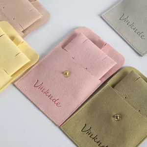 Detailed close-up of colorful suede jewelry pouches with snap buttons and elegant logos