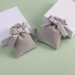 Grey velvet jewelry drawstring pouches with satin ribbon bows on gift boxes