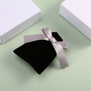 Détail macro d'une pochette à bijoux en velours noir avec nœud décoratif en ruban gris