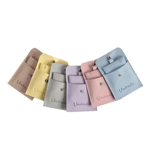 Set of six colorful velvet jewelry pouches with snap closures arranged in a decorative fan shape