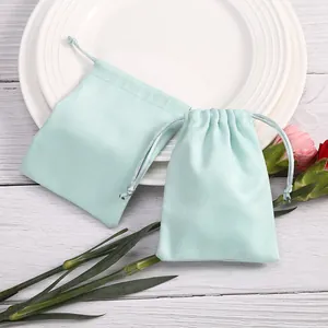 Dos elegantes bolsas de terciopelo verde menta para joyas sobre un plato blanco liso
