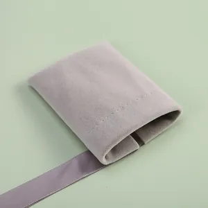 Elegant close-up of a gray velvet jewelry pouch with soft ribbon detail and stitching