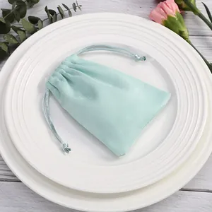 Elegante bolsa de terciopelo verde menta para joyas presentada en un plato blanco