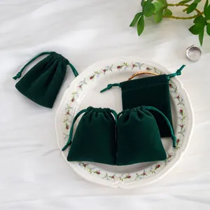 Primer plano detallado de bolsas para joyas de microfibra verde oscuro en un plato