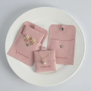Premium pink double-sided suede jewelry pouches with snap buttons on a white plate