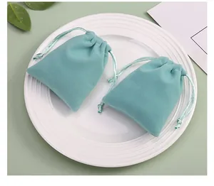 Deux pochettes à bijoux en velours vert menthe haut de gamme sur une assiette en céramique