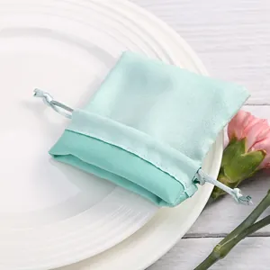 Detalle de bolsa de joyería de terciopelo verde menta en plato blanco.