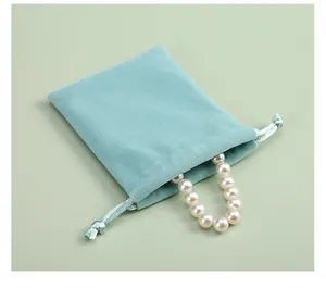 Gros plan d'une pochette à bijoux en velours bleu clair avec un collier de perles