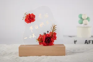 Vue détaillée de fleurs rouges préservées sur une veilleuse en acrylique lumineuse en bois