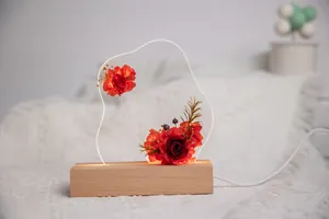 Gros plan de roses rouges éternelles dans une veilleuse en acrylique éclairée au socle en bois