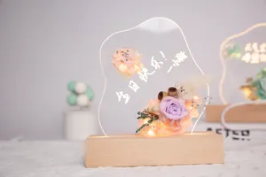 Gros plan d'une veilleuse en acrylique avec fleurs éternelles et base en bois lumineux
