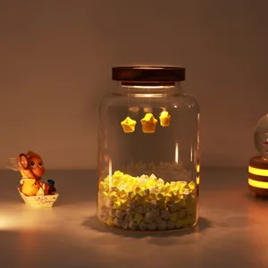 Decorative glass jar night light with warm LED glow and yellow paper stars inside