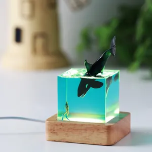 Close-up of ocean whale night light featuring orca and diver in transparent blue resin