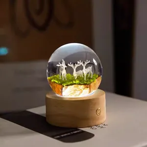 Elegant resin crystal ball night light featuring deer figurines on a warm wooden base