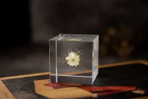 Gros plan détaillé d'une fleur blanche préservée dans un cube en résine transparente.