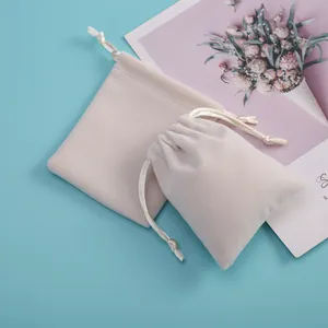 Primer plano de bolsas de terciopelo blanco crema para joyas con cierre de cordón.