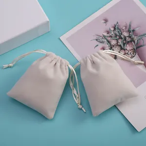 Primer plano de pequeñas bolsas de terciopelo crema para joyería en fondo azul
