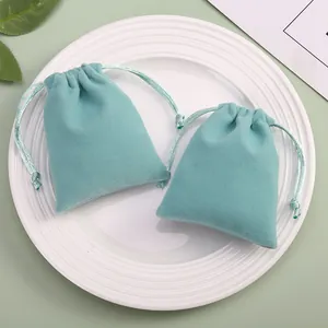 Deux pochettes en velours vert menthe avec cordon pour bijoux et cadeaux sur plateau