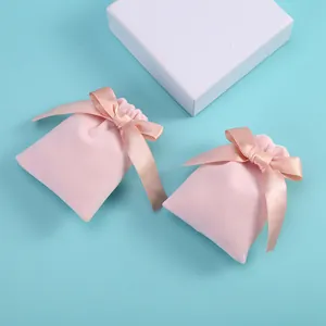 Détail de deux pochettes à bijoux en velours rose avec cordon et nœuds en satin